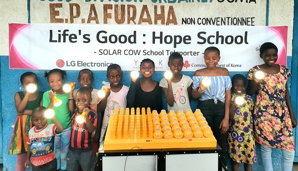 (사진: LG전자) 프라하(Furaha) 초등학교 학생들이 LG전자가 설치한 친환경 태양광 충전시스템 '솔라카우'를 이용해 충전한 휴대용 보조 배터리를 사용하며 기뻐하고 있다.