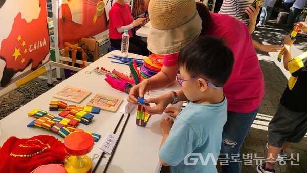 (사진제공 : 성북구) 세계 전통 놀이기구 체험을 위해 설명을 듣고 있는 어린이의 모습